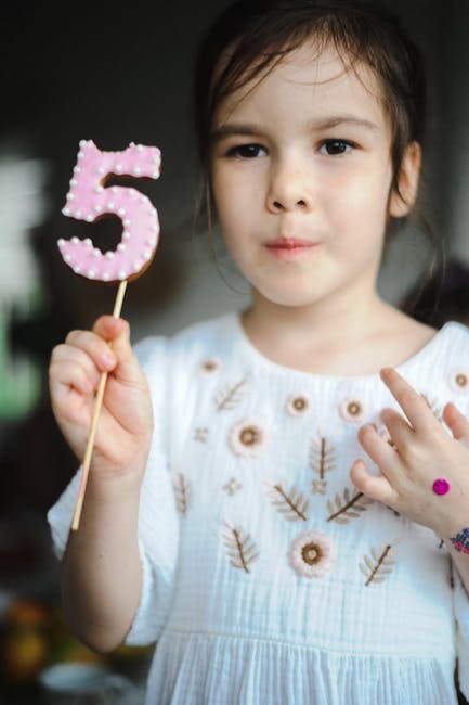 A young child holding a number five representing future growth and heritage